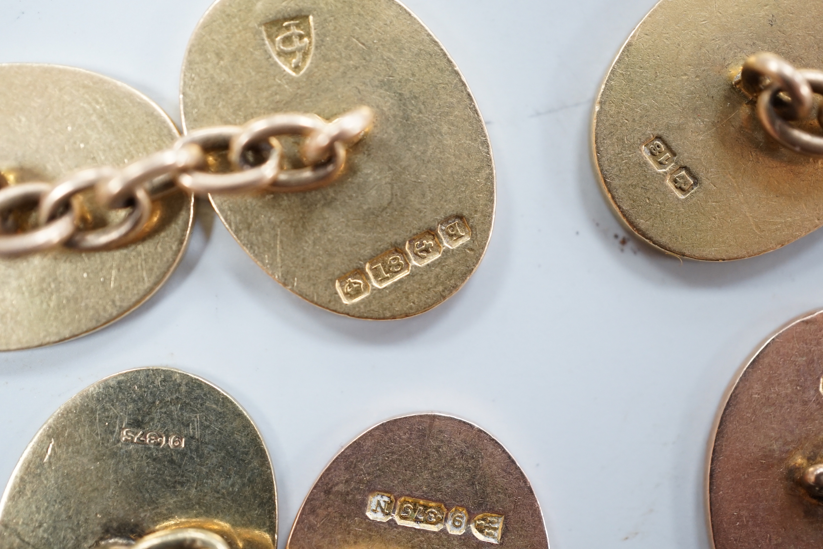 A pair of George V 18ct gold oval cufflinks, with engraved crest and initials, G.H. Johnstone & Co, Birmingham, 1915, 16.7 grams and a pair of late Victorian engraved 9ct gold oval cufflinks, 6.7 grams.